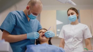 Diş hekimi koltuğundaki kadın diş hekimini muayene etsin. Dişlerine dikkat etsin.