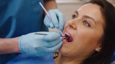 Kameraya yakın olan güzel bir kadın modern bir diş sağlığı kliniğinde sözlü muayeneye tabi tutuluyor.