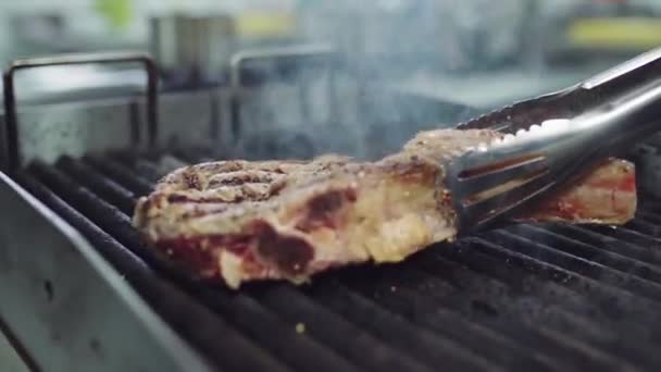 职业厨房烤肉厨师在摄像机前做牛肉牛排，他把牛排扔在烤肉架上 — 图库视频影像