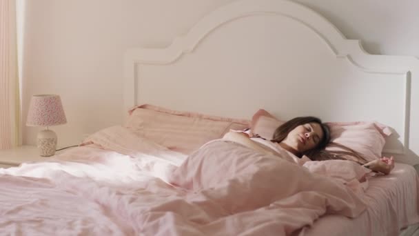 Güzel kahverengi saçlı bir kadının güzel pijamaları ve yorganlarıyla uyuduğu bir arka açı. — Stok video