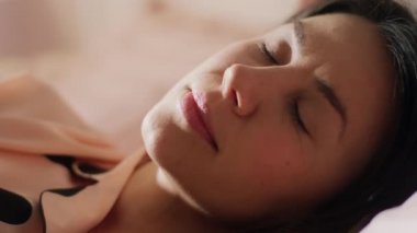 Parlak pembe bir yatak odasında uyanan genç bir kadının yakın plan çekimi güne başlamak için çok hevesli.