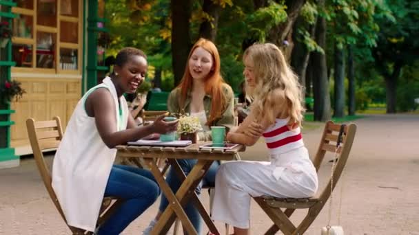 Sonriendo a la gran dama africana y sus bonitos amigos en el café se encuentran una a otra dama africana mostrando algo en sus damas de teléfonos inteligentes discutiendo entre sí — Vídeos de Stock