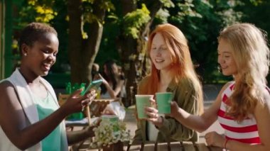 Büyük bir gülümseme ile çok ırkçı bir grup bayan ve akıllı telefondan bazı fotoğraflar çektikten sonra kafede çok heyecanlılar. Sonuçlara baktıklarında mutlular ve harika hissediyorlar.