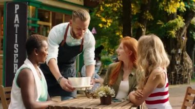 Parkın ortasında barista bir grup çok ırklı arkadaşa kahve getiriyor. Mutlular ve gülümsüyorlar.