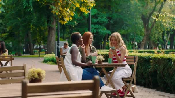 在公园中央的松饼店，一群快乐而兴奋的女士从智能手机里拿出一些自拍 — 图库视频影像