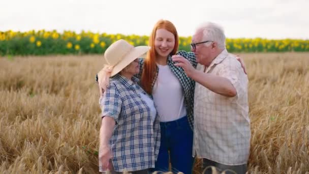 Famiglia concetto aziendale nonni agricoltori e la loro bella nipote nel bel mezzo di un grande campo di grano felice abbracciarsi — Video Stock