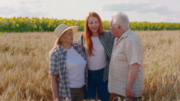 Bella giovane donna ei suoi nonni in posa davanti alla telecamera nel mezzo del concetto di campo di grano di azienda agricola familiare. Girato su ARRI Alexa Mini. — Video Stock