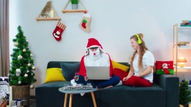Evde, kanepede, kadın ve erkek, kulaklıklardan müzik dinlerken ve Noel Baba battaniyesindeki adam dizüstü bilgisayardan bakarken dans ederken eğleniyorlar. ARRI Alexa 'da çekim