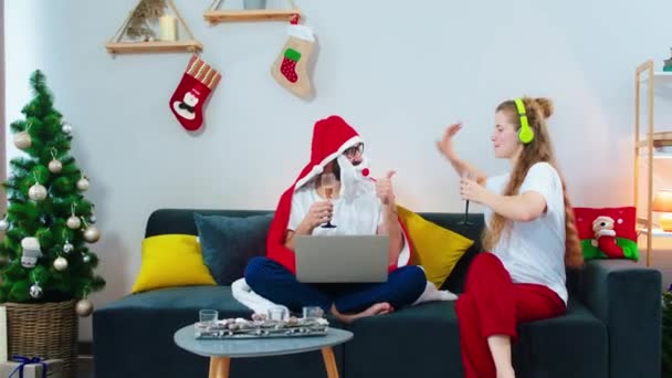 In the living room dancing happy and excited lady and cheers with glasses of champagne with her boyfriend while he are watching something on the laptop while wearing a Santa blanket. Shot on ARRI — 비디오