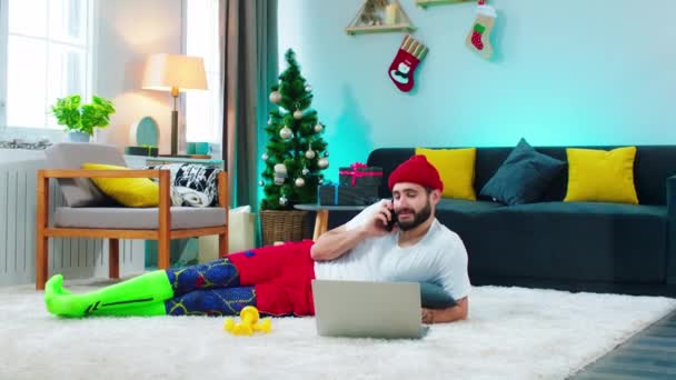 Large spacious living room a man using the laptop to order something online and take the phone to make a call happy and excited he speaking on the phone — 图库视频影像