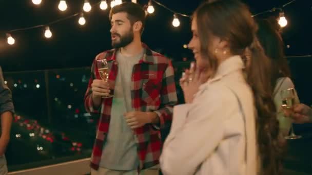 Мультирасовые люди весело проводят время на террасе вечером они наслаждаются время обсуждая друг с другом и пить шампанское — стоковое видео