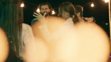 Terasın çatısında büyük bir parti zamanı gençler gecenin tadını çıkarıyorlar müzik dinliyorlar şampanya içip dans ediyorlar