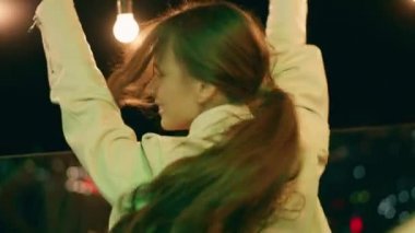 Uzun saçlı mutlu ve heyecanlı bayan çatıdaki terasta arkadaşlarıyla eğleniyor.