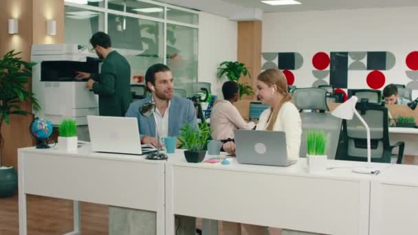 Um homem e uma mulher estão no trabalho falando sobre negócios, ambos parecem muito felizes, eles estão no escritório que tem uma atmosfera animada — Vídeo de Stock