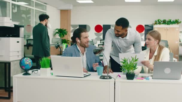 Drie collega 's hebben een leuk gesprek op het werk op kantoor, terwijl ze lachen komt hun manager opdagen en één van hen vertrekt, ze beginnen weer te werken — Stockvideo