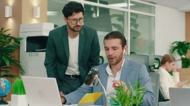 İki asistan sabah büyük bir ofiste sakallı ve gözlüklü yakışıklı müdürlerine laptopta yaptıkları işi gösteriyorlar.