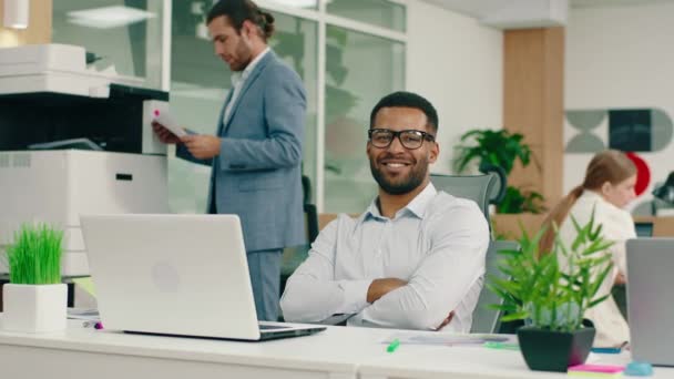 Egy nagyon jóképű fekete fiatalember egy esztétikai irodában ül, miközben a székében ül, keresztbe teszi a karját és széles mosollyal mosolyog. — Stock videók
