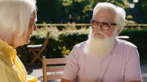 Sommerzeit Nahaufnahme der Kamera erstaunliche alte Pärchen europäisch suchen Beschleunigung romantische Zeit zusammen im Café in der Mitte des Parks — Stockvideo