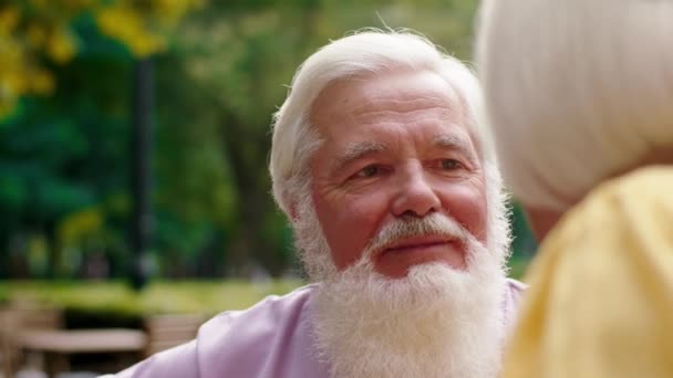 Carismático anciano con amor mirando a su esposa mientras acelera el tiempo romántico en el café en medio del parque. 4k — Vídeos de Stock