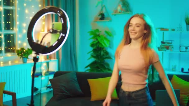 İyi görünümlü genç bir kadın etkileyicisi sosyal medya hesabı için akıllı telefonuyla ve ışık halkasıyla video kaydediyor. — Stok video