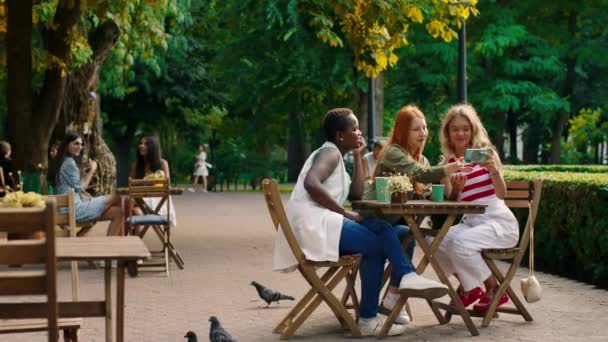 Selfie χρόνο για μια ομάδα καταπληκτική πολυφυλετικές όμορφες κυρίες, ενώ κάθεται στο καφέ στη μέση του πάρκου παίρνουν φωτογραφίες με smartphone. 4ια — Αρχείο Βίντεο