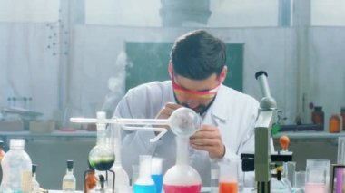 Kimya laboratuvarında bazı deneyler yapan konsantre olmuş bilim adamı bir reaksiyon yaratmak için kimyasal sıvı eklemiş.