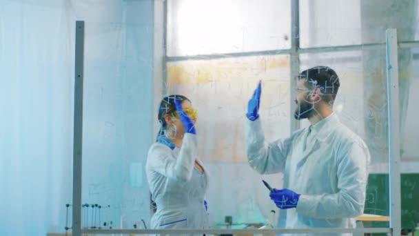 Skvělý chemický tým v laboratorní dámě a muž dávat pět navzájem poté, co skončí psát chemický vzorec na transparentní tabuli — Stock video