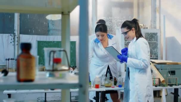 화학 실험실에서 두 명의 카리스마있는 여성 과 한 명의 남자 의대 생이 화학 공식 과 디지털 태블릿을 혼합 한 몇 가지 실험을 했습니다. — 비디오