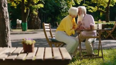 Çekici yaşlı kadın ve karizmatik yaşlı adam parkta romantik vakit geçiriyorlar. Birbirlerine sarılıp öpüşüyorlar.