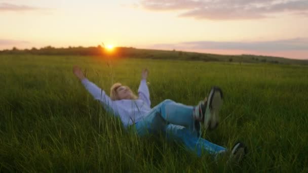 Increíble vista en medio de la naturaleza dama cayendo sobre la hierba al atardecer disfrutar del momento a solas. Disparo en ARRI Alexa Mini. — Vídeo de stock