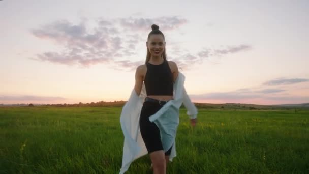 Schöne große Dame vor der Kamera Bei Sonnenuntergang genießen Sie den Moment, wenn Sie durch das grüne Feld gehen — Stockvideo