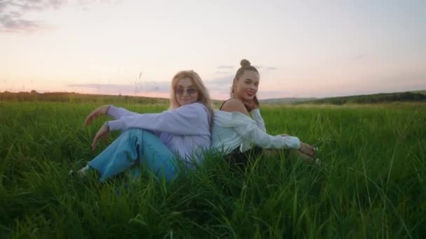 Ao pôr do sol no meio de um grande campo verde feliz e relaxado duas melhores amigas senhoras desfrutar do tempo juntos — Vídeo de Stock