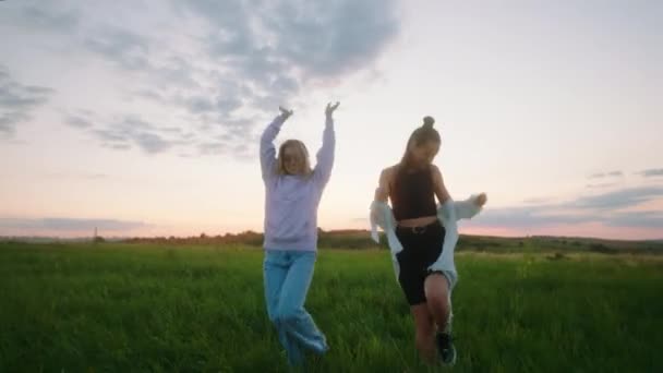 Gehen und Tanzen vor der Kamera durch das grüne Feld charismatische und schöne Damen beste Freunde — Stockvideo