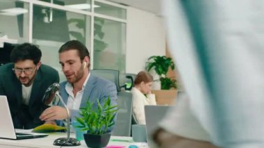 Kahverengi saçlı çalışkan bir adam dizüstü bilgisayarında başardığı işi müdürüne gösteriyor. Harika bir ofisteler. Arri Alexa Mini.