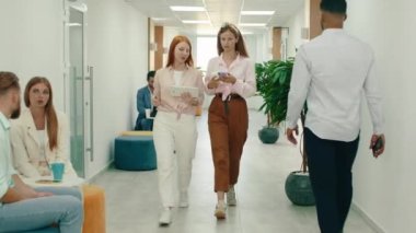 İki çok çekici ve zeki kadın ofis koridorunda yürüyorlar ve bir sürü çalışkan insanın yanından geçerken işe giriyorlar.