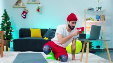 Yakışıklı adam sıkı çalışmasını bitirdikten sonra oturma odasında yerde otururken dizüstü bilgisayarını kullanıyor ve online üniversite kursuna başlıyor.