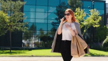 Güneşli bir günde ekolojik alışveriş torbalarıyla harika bir bayan kameranın önünde yürüyor ve akıllı telefonuyla birkaçıyla sohbet ediyor. Arri Alexa Mini.