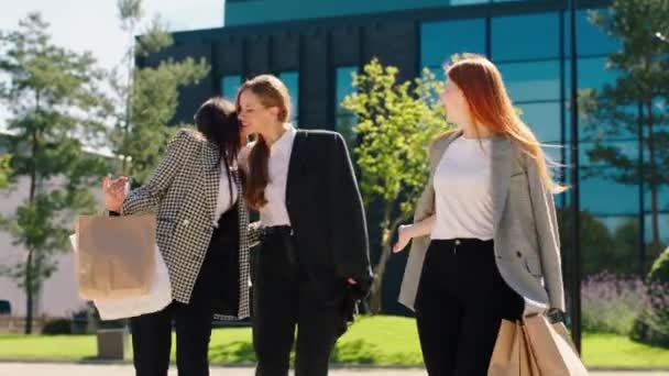 Feliz grupo de damas que se reúnen en la tienda después de un duro día de trabajo desde la oficina se abrazan y caminan delante de la cámara mientras sostienen bolsas de compras — Vídeos de Stock