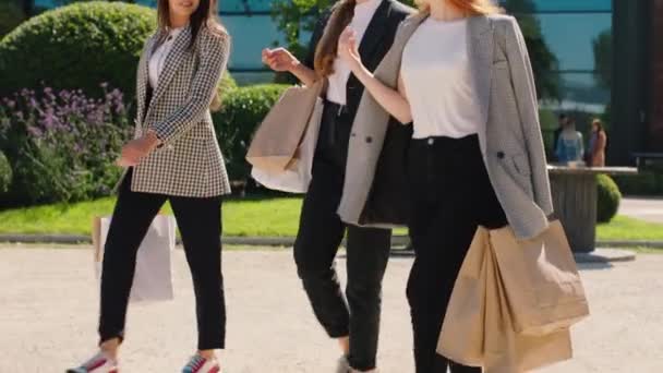 Lächelnd große charismatische schöne Frauen nach einem guten Einkauf zu Fuß die Straße hinunter diskutieren zusammen und glücklich halten Öko-Einkaufstaschen Hintergrund erstaunlich hohe Gebäude — Stockvideo