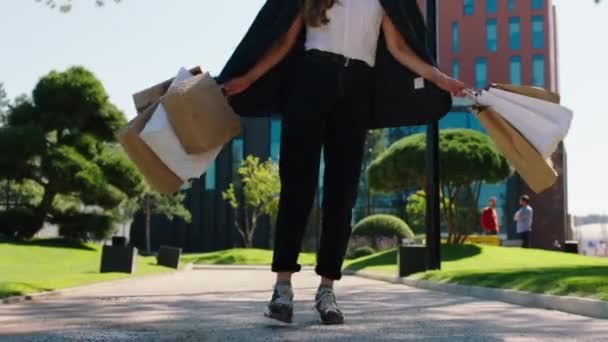 Modernt köpcentrum glad dam efter en bra shopping hålla några eco shoppingväskor och hoppa upphetsad närbild fånga ben och shoppingväskor — Stockvideo