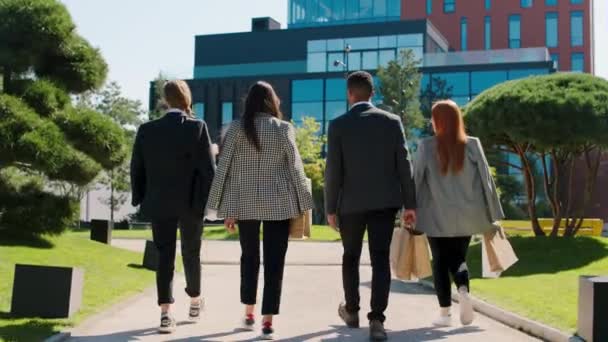 Grupo multiétnico de colegas trabajadores de oficina caminando a su principal centro de negocios después de la hora del almuerzo que sostienen algunas bolsas de compras — Vídeos de Stock