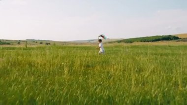 Yeşil tarlanın ortasında küçük çocuk mutlu ve heyecanlı büyük bir gülümsemeyle koşuyor ve sevimli köpeğiyle kameranın önünde oynuyor.