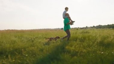 Sırtında küçük sevimli oğluyla birlikte büyük bir gülümseme ile doğada koşan bir adama ve ardından küçük şirin bir İngiliz cocker spaniel 'i koşturan bir köpeğe. ARRI Alexa Mini 'de çekilen.