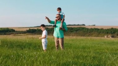 Çekici bir adam ve doğadaki iki küçük çocuğu geniş bir arazinin ortasında durup babalarının oğullarıyla tartıştığı bir şeyi analiz ediyorlar. ARRI 'de çekilen