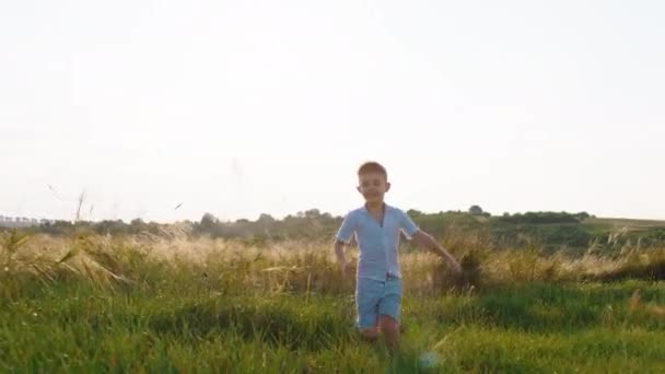 Luonnossa käynnissä nopea söpö pieni poika, jolla on suuri hymy, hän nauttii hetkestä luonnossa ottamalla videon lähikuva kameran edessä. — kuvapankkivideo