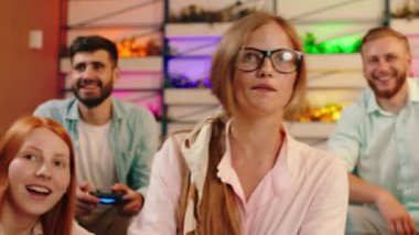 Uzun sarı saçlı ve gözlüklü bir kadın video oyunları oynarken heyecanlanıyor ve etrafındaki diğer kadınlar onun kazanması için tezahürat yapıyor. Arri Alexa Mini.