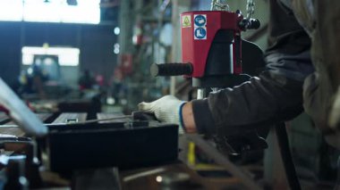 Demircideki kameraya yakın çekim, metal işçiliğini başlatmak için ağır makineyi tamir ediyor..