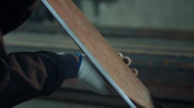 Endüstriyel fabrikada ayrıntıları alan kameraya yakın demirci elinde düz bir metal parçası tutuyor..