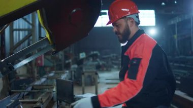 Üretim bölgesindeki endüstriyel fabrikada ağır makinelerde çalışan güvenlik ekipmanlarıyla çalışan fabrika işçisi. 4k