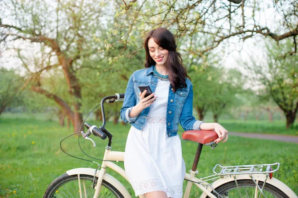 Frau mit Fahrrad mit Smartphone unterwegs — Stockfoto